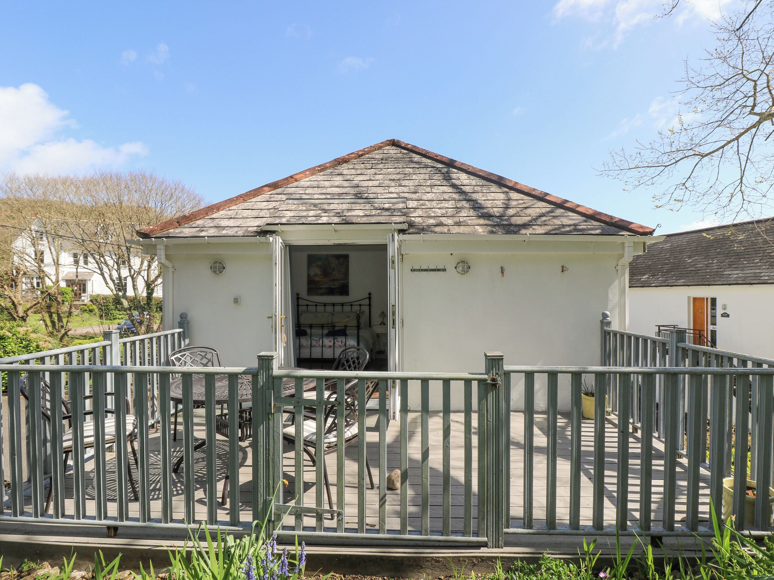 A small, white building with a sloped roof, a single door, and a small porch area.