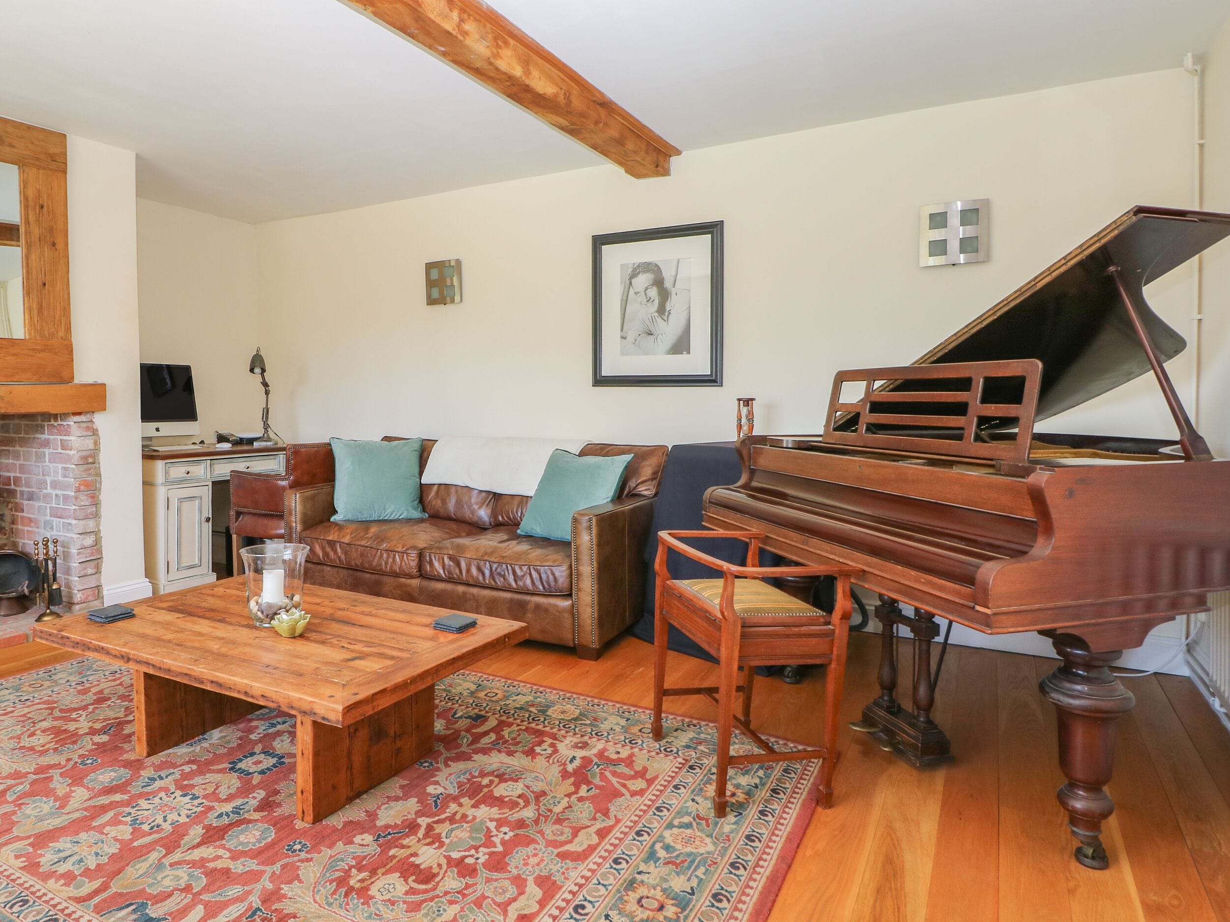 A living room with a wooden coffee table, a brown leather sofa, a blue armchair, and a grand piano.