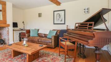 A living room with a wooden coffee table, a brown leather sofa, a blue armchair, and a grand piano.