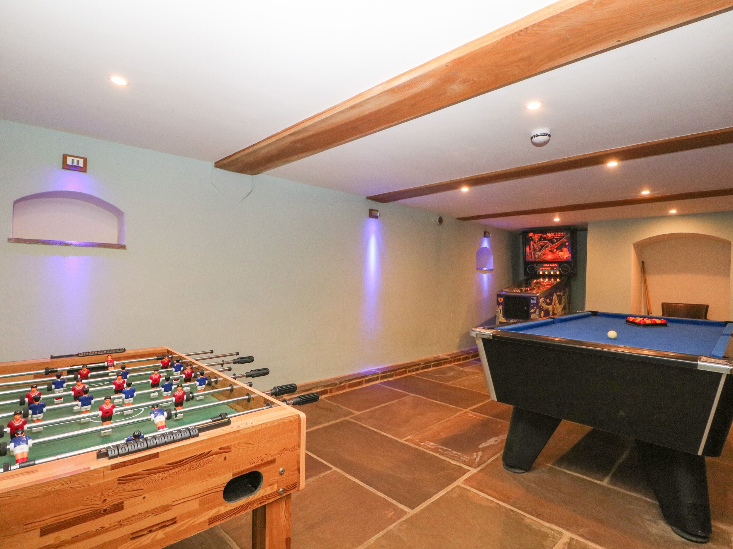 A room with a foosball table and a pool table.