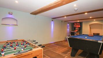 A room with a foosball table and a pool table.