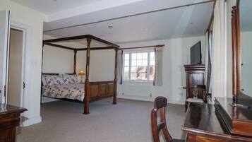 A bedroom with a four-poster bed, a desk with a mirror, and a television.
