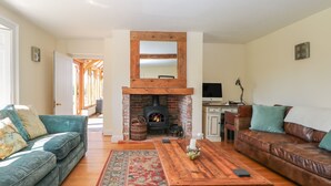 A living room with a fireplace, a sofa, a coffee table, and a television. - Groomes Country House (Bordon)