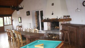 Ein Essbereich mit Billardtisch, Holzsesseln, Kamin und Bar.