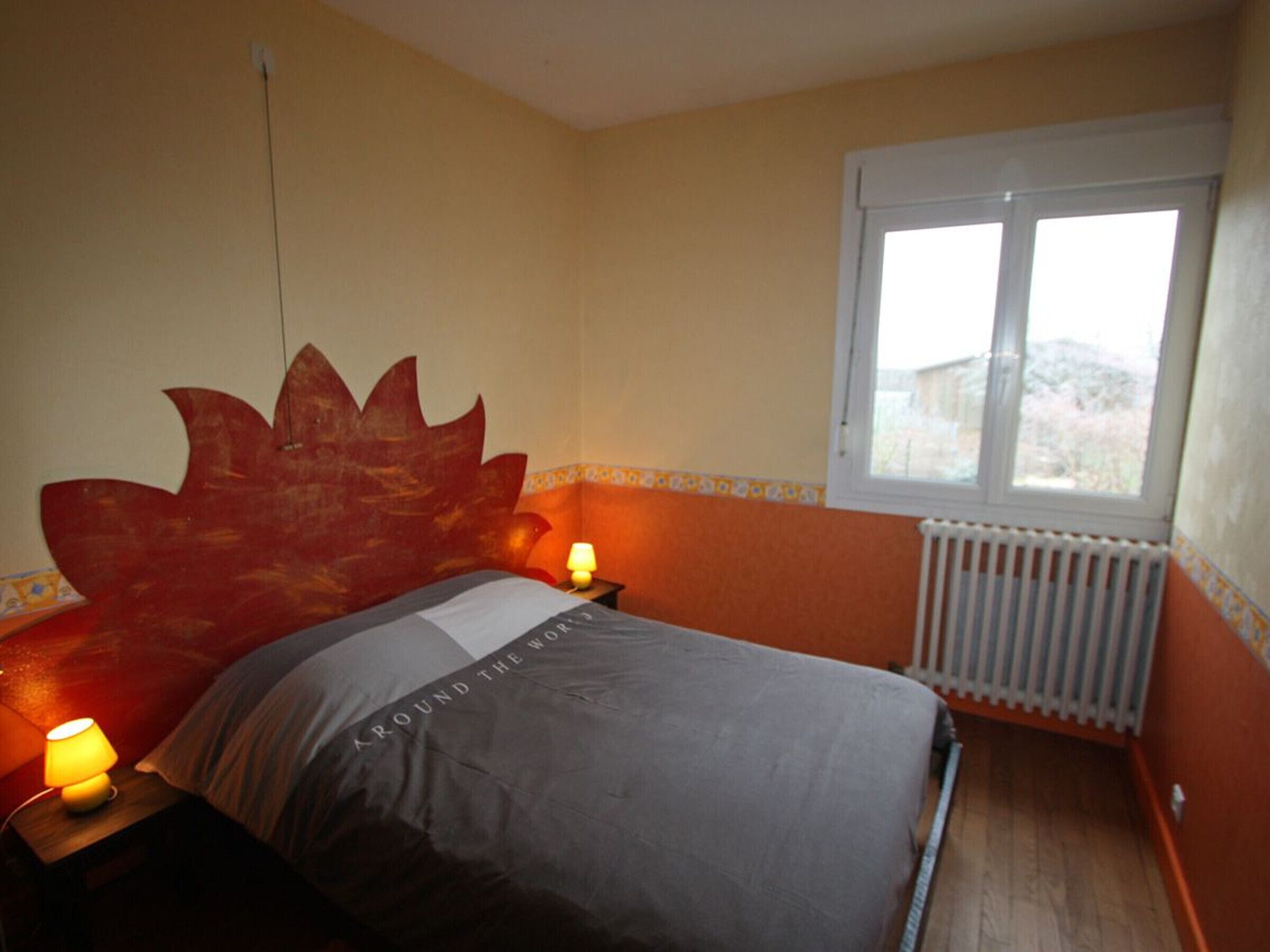 Une chambre à coucher avec un lit, une fenêtre et un radiateur.