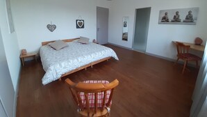 Ein geräumiges Schlafzimmer mit einem großen Bett, Holzboden und einem Sessel.