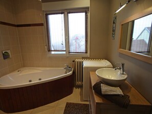 A bathroom with a freestanding bathtub, a sink, and a window with blinds.