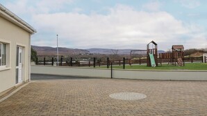 A paved courtyard with a playground, a fence, and a building in the background.