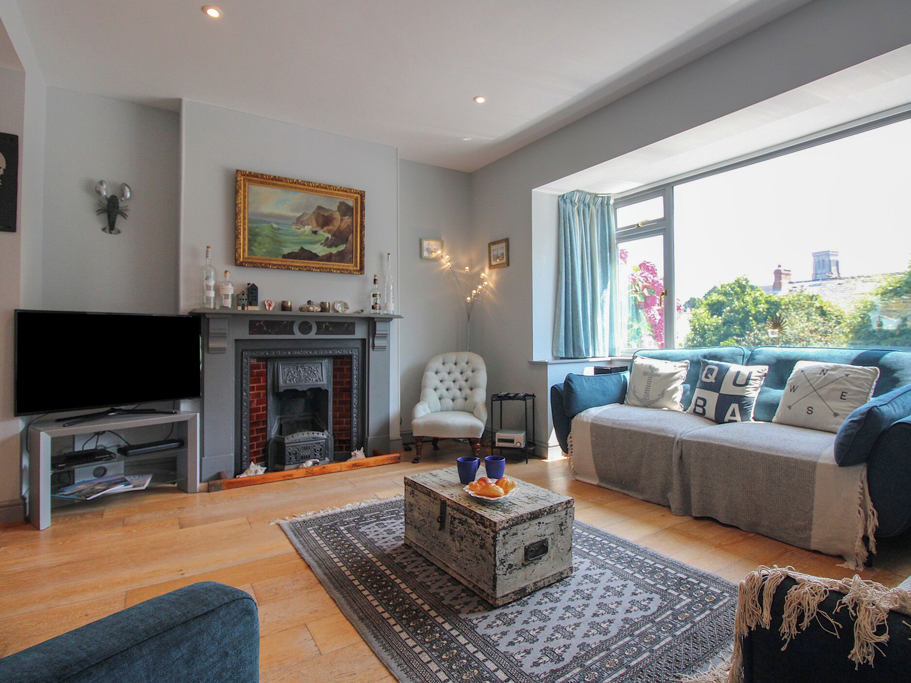 A living room with a fireplace, television, sofa, and a view of the city.