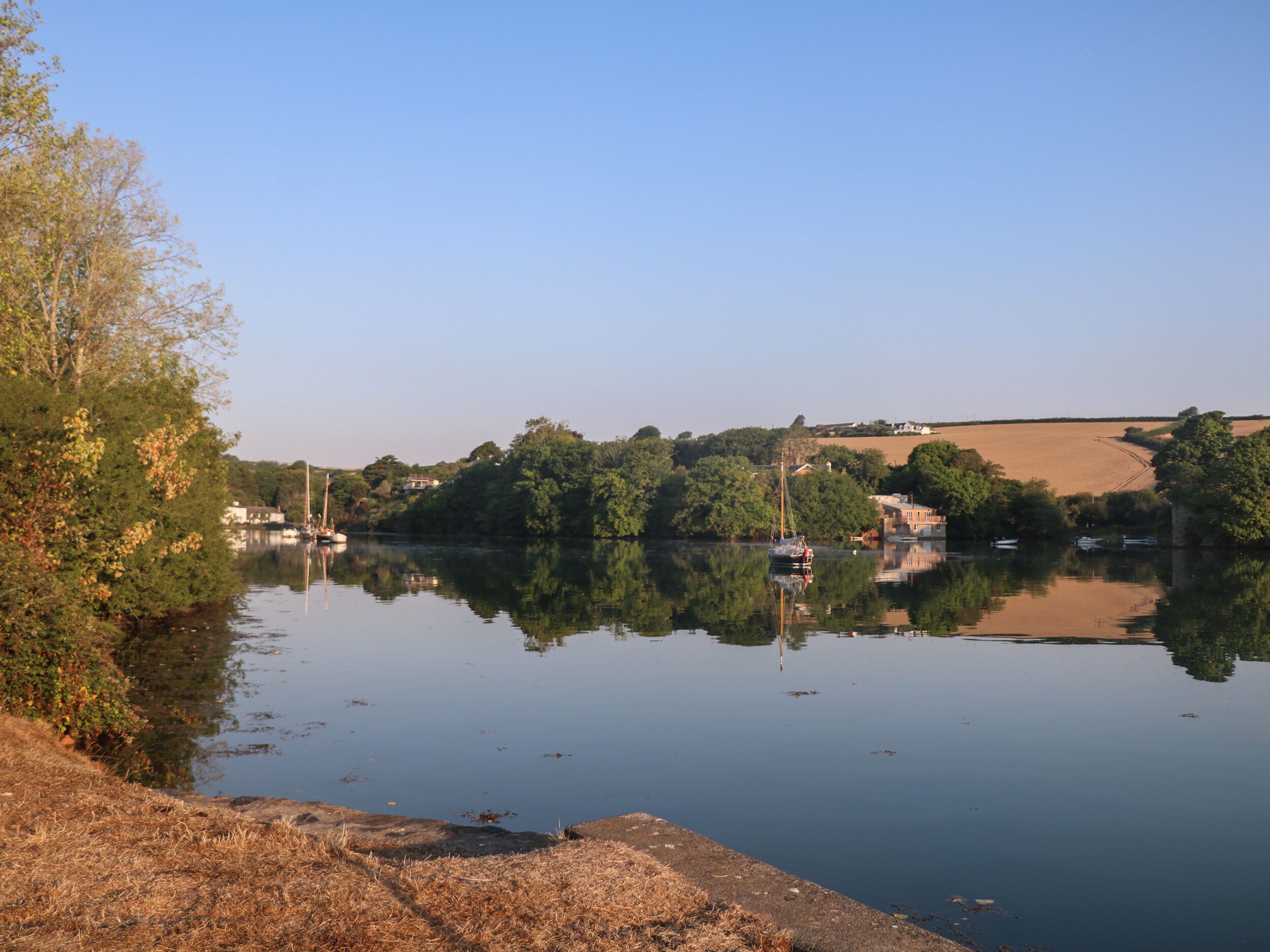 Un río tranquilo con barcos, rodeado de árboles y edificios.