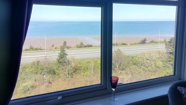 Una habitación con un ventanal grande que da a una playa y una autopista.