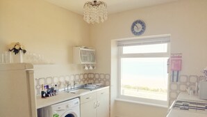 Una cocina compacta con lavadora, un lavabo y una ventana con vistas.