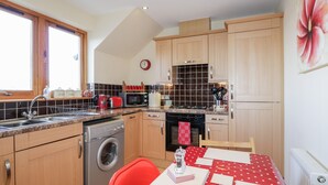 Una cucina con mobili in legno, una lavatrice, un forno a microonde e un piano cottura.