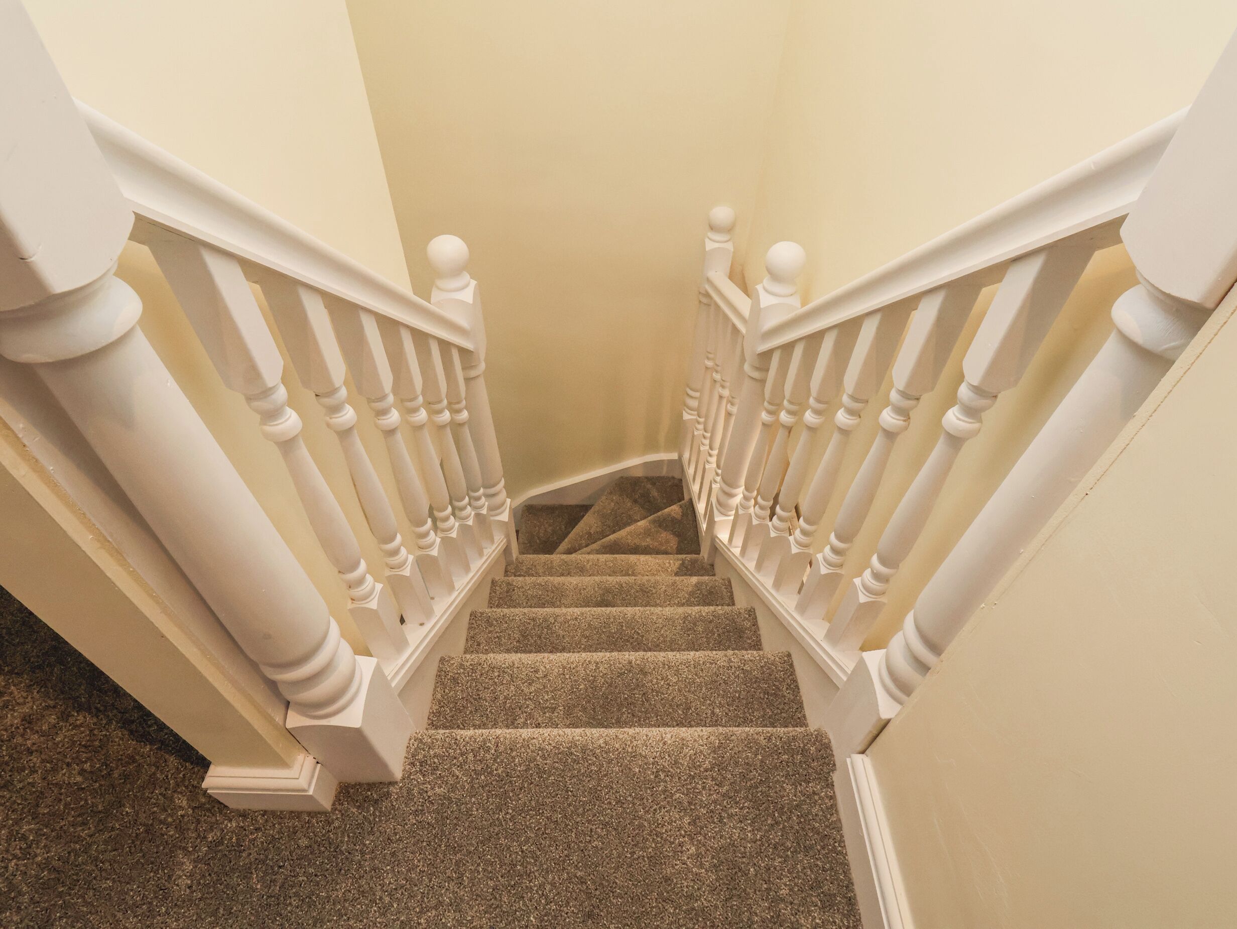 A staircase with white balusters and a carpeted floor.