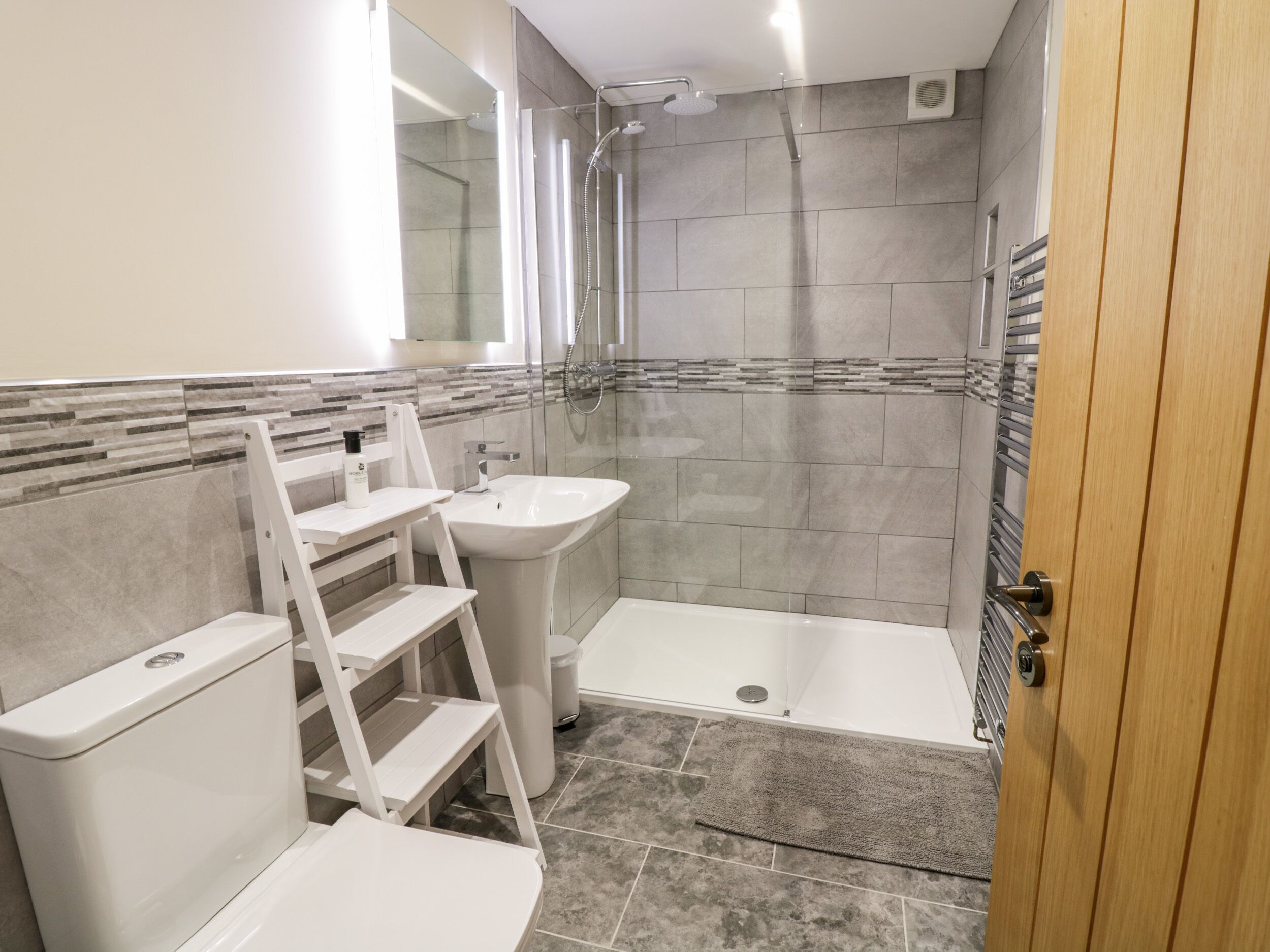 A modern bathroom with a shower, toilet, and sink.