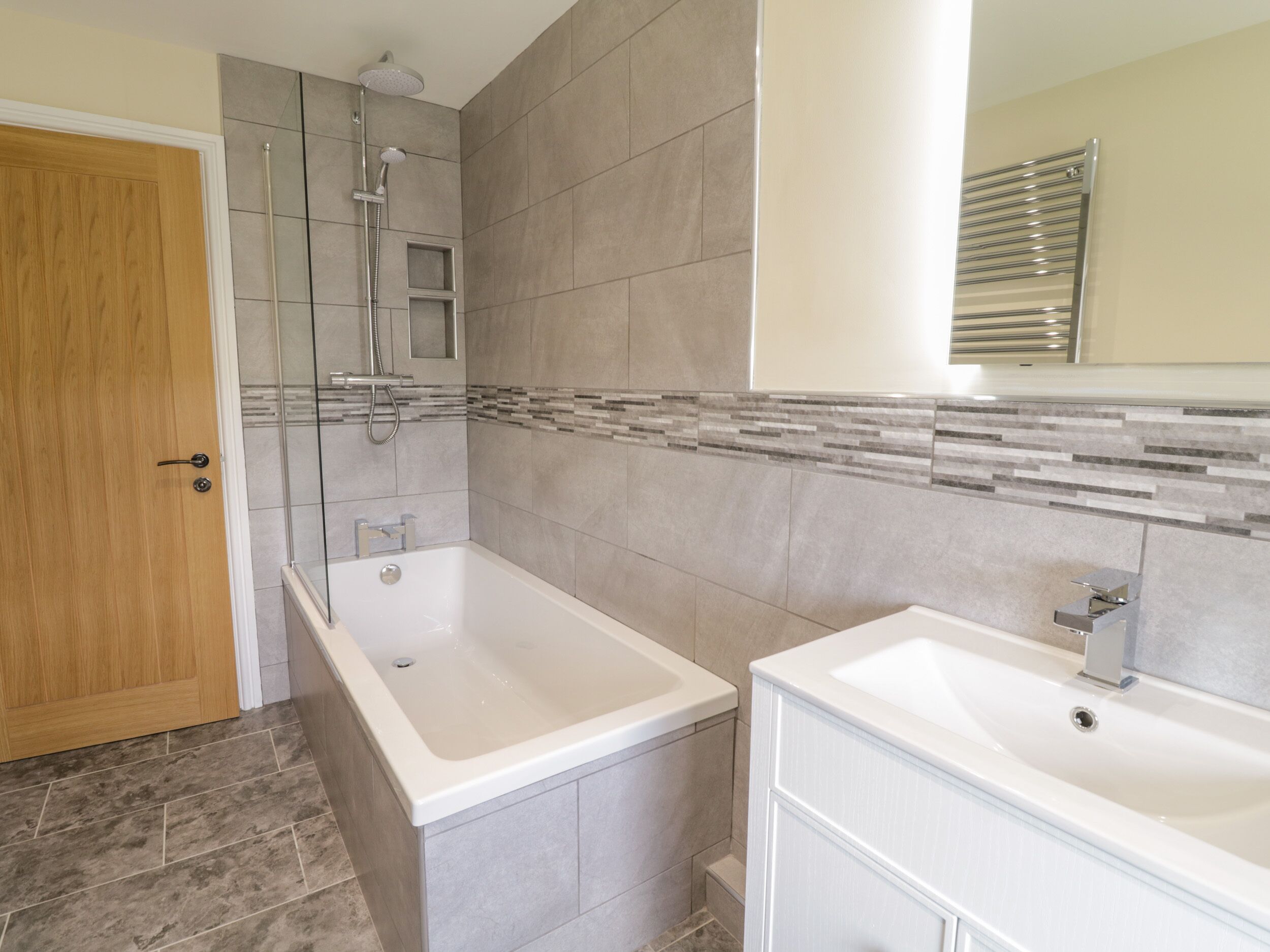 Une salle de bain avec une douche, deux lavabos et une porte en bois.