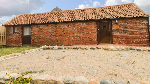 A brick building with a tiled roof, a wooden door, and a sign reading "Honeybee Cottage". - Honeybee Cottage (Hull)