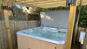 A wooden deck with a hot tub, two wooden steps, and a pergola overhead. - Y Gogarth (Tyn-y-Gongl)