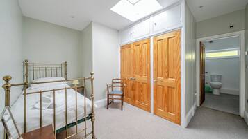 A bedroom with a bed, a chair, a wardrobe, and a bathroom.