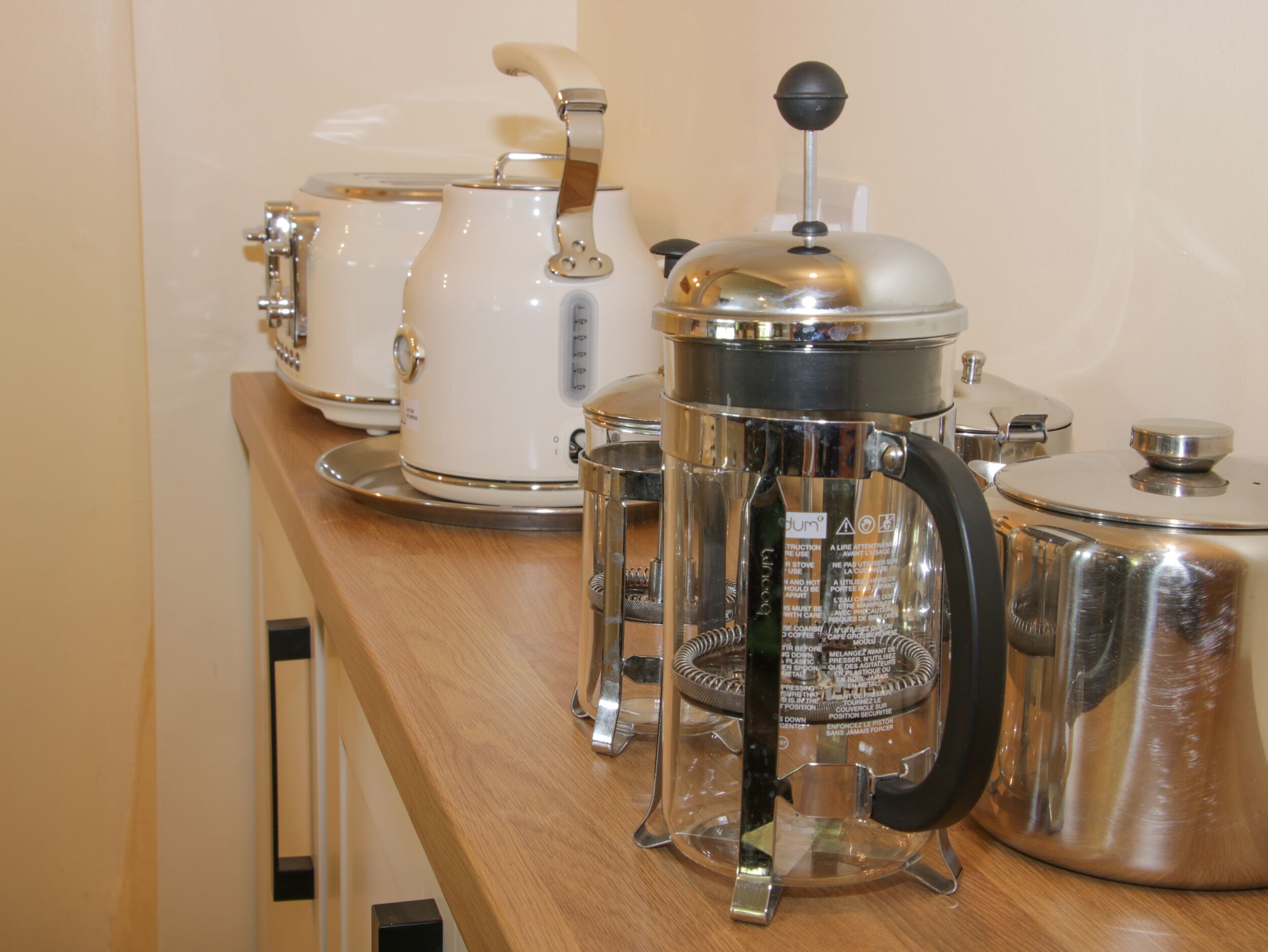 En köksbänk med olika typer av kaffebryggare, inklusive en presskanna, en kaffekanna och en perkulator.