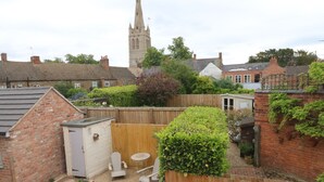 A backyard with a wooden fence, a small shed, and a garden area with a bird feeder. - Bennett's Cottage (Oakham)