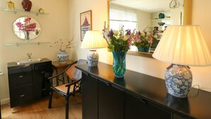Una habitación con un escritorio negro, dos lámparas, un espejo y un florero con flores.