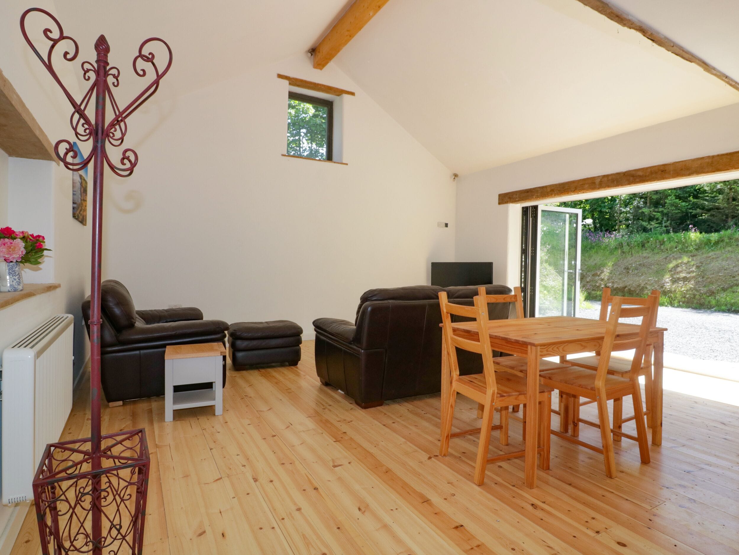 Un grand espace de vie doté d’un plancher en bois, d’une table à manger avec des chaises, d’un canapé et d’un téléviseur.
