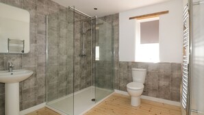 A bathroom with a glass-enclosed shower, a white sink, and a toilet. - The Cart House (St Austell)