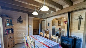 Ein Holzinnenraum mit Esstisch, Stühlen, Küchenzeile und Kamin.
