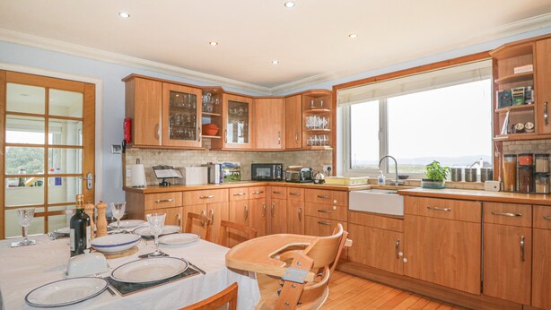 A kitchen with wooden cabinets, a dining table set for four, and a window providing a view.
