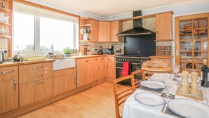 A kitchen with wooden cabinets, a stove, and a dining area set for six.