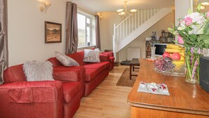A living room with a red sofa, a wooden coffee table, and a staircase leading to a loft area.