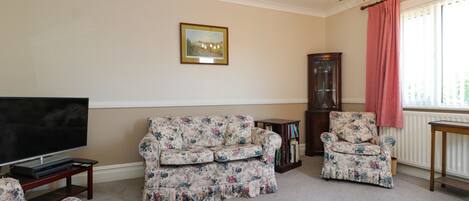 A living room with a sofa, armchair, and a television.