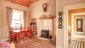A cozy living room with a fireplace, wooden furniture, and a dining area with a table and chairs. - Newtown East (Newtown East)