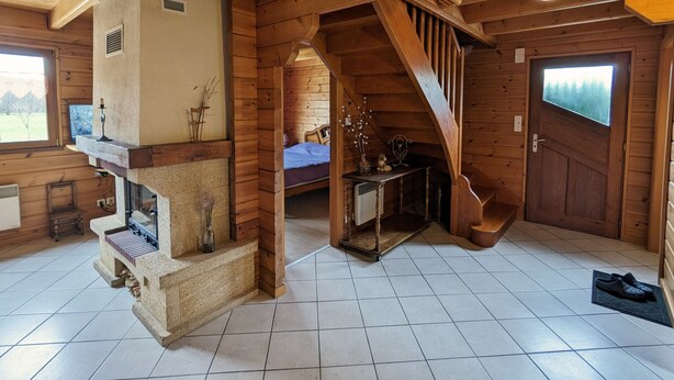A log cabin interior with a fireplace, a bed, and a staircase. - Cosy Chalet near Ski Resorts with Terrace and Forest Trails (Vagney)