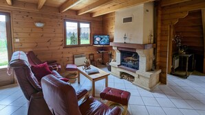 A cozy cabin interior with wooden walls, a fireplace, a television, and leather seating. - Cosy Chalet near Ski Resorts with Terrace and Forest Trails (Vagney)