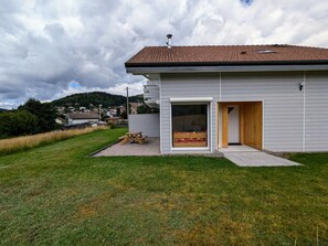 A modern house with a tiled roof, a wooden door, and a picnic table in the yard.