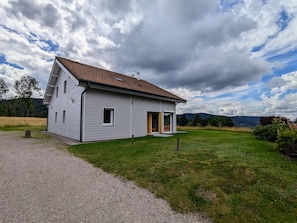 A single-story house with a sloped roof, a front porch, and a gravel driveway.