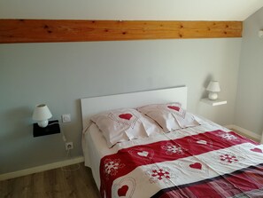 A bed with a white headboard, a red and white patterned bedspread, and two bedside lamps on white nightstands.