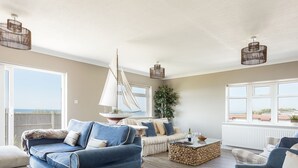 A spacious living room with a blue sofa, a wooden coffee table, and a sailboat decoration. - Beach Haven (Dorchester)
