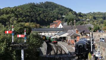 A railway station with tracks, a platform, and a building with a traditional architectural style.