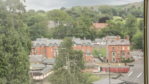 A view of a town with red brick buildings, including a hotel with a sign "Celtic Glen Y Gales." - Whitewater Cottage (Llangollen)