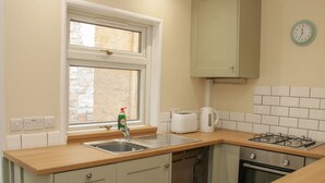 A kitchen with a window, a sink, a toaster, a kettle, and a stove. - Whitewater Cottage (Llangollen)