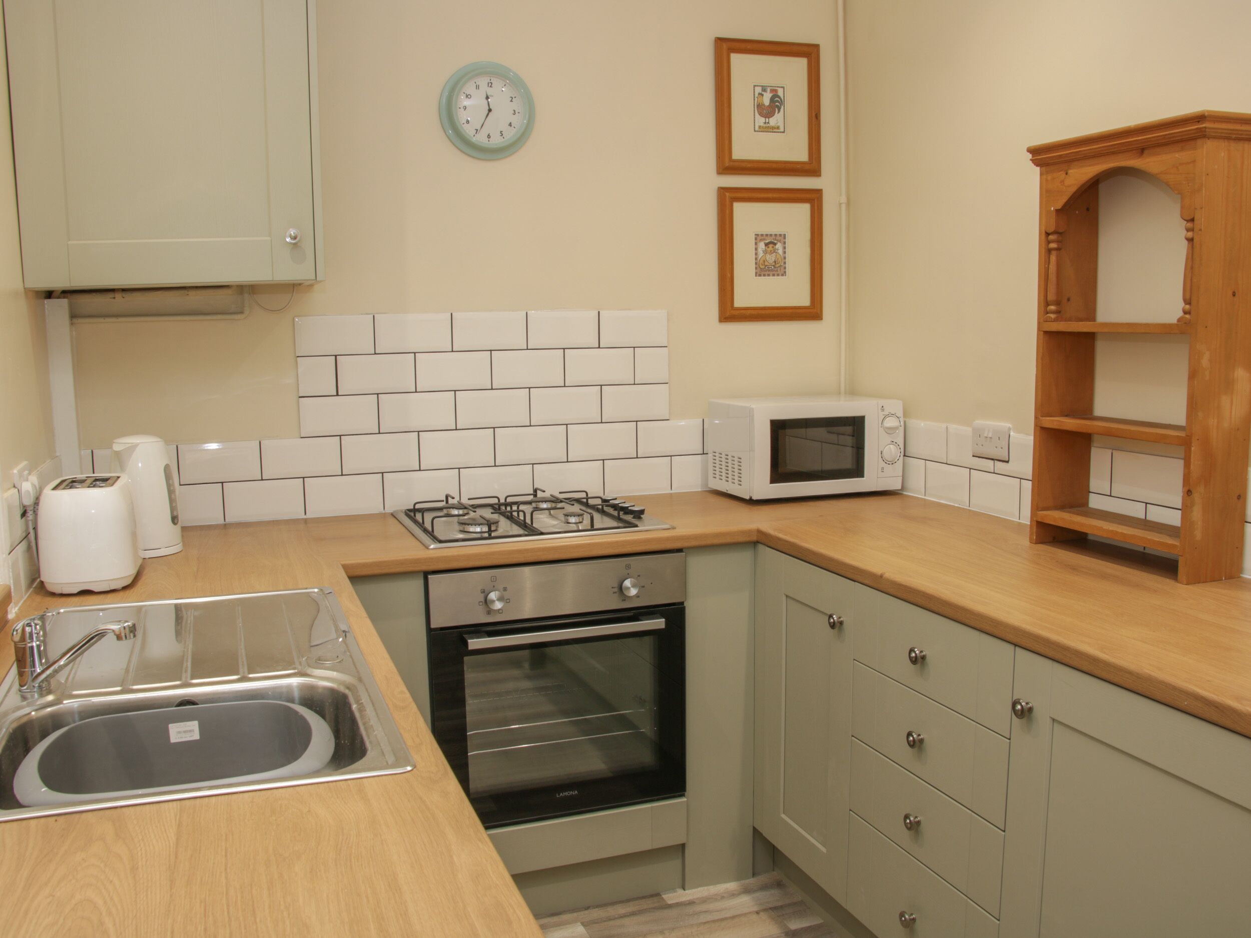 A kitchen with a gas stove, oven, microwave, sink, and wooden cabinets.