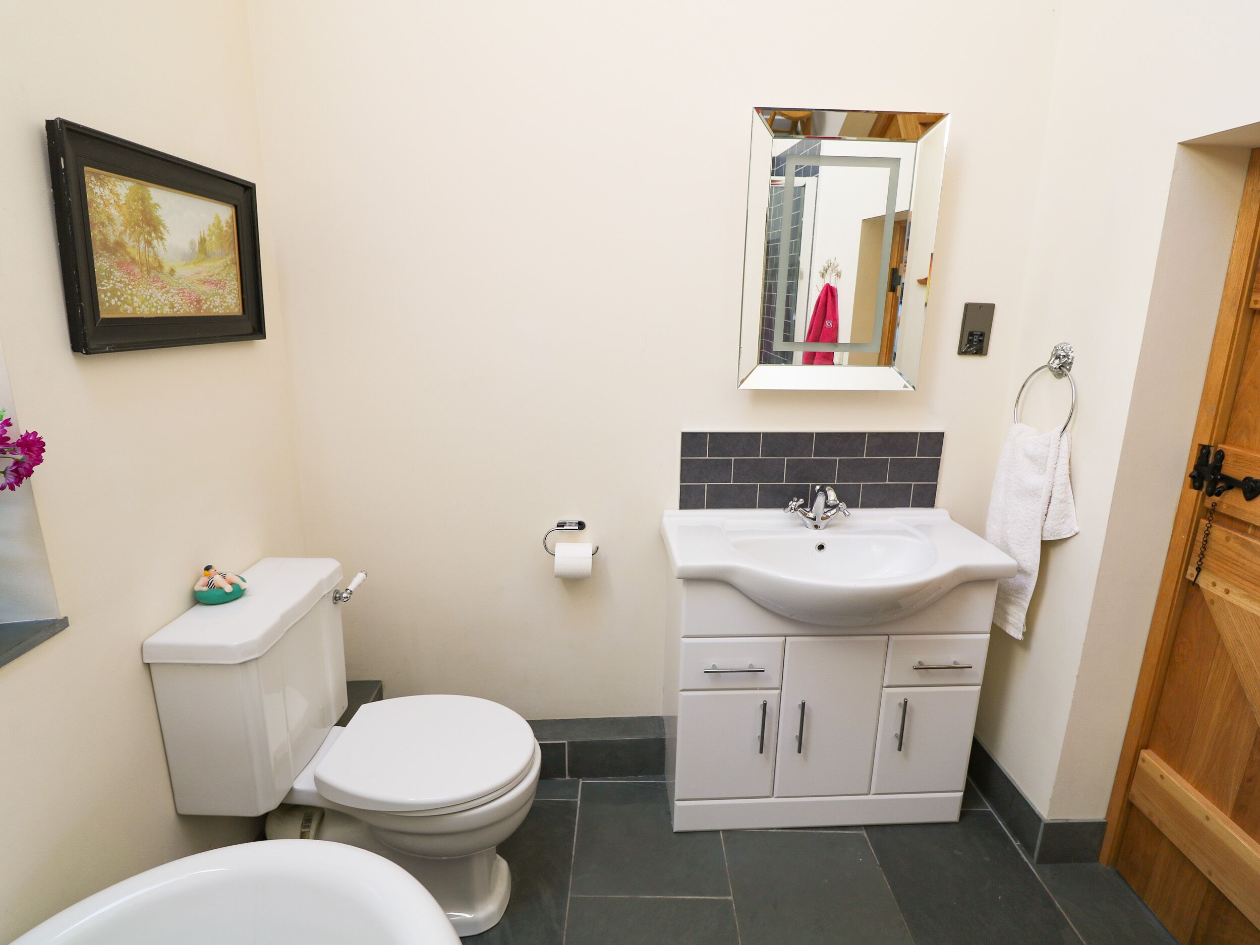 A bathroom with a toilet, sink, and mirror.