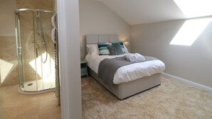 A bedroom with a skylight, a walk-in shower, and a bed with a view of the sky.
