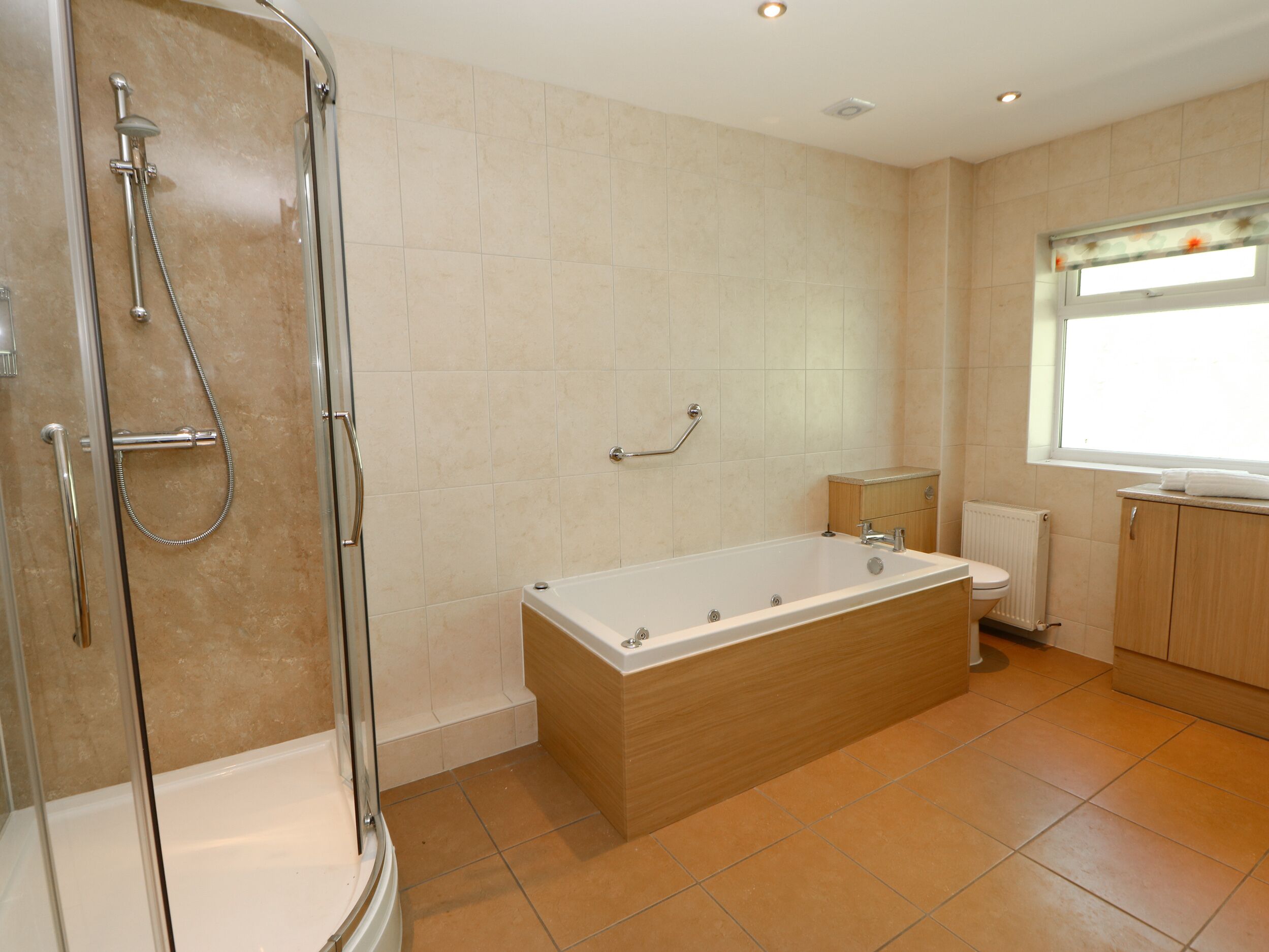 Une salle de bain moderne avec une douche à l’italienne, une baignoire sur pieds et des toilettes.