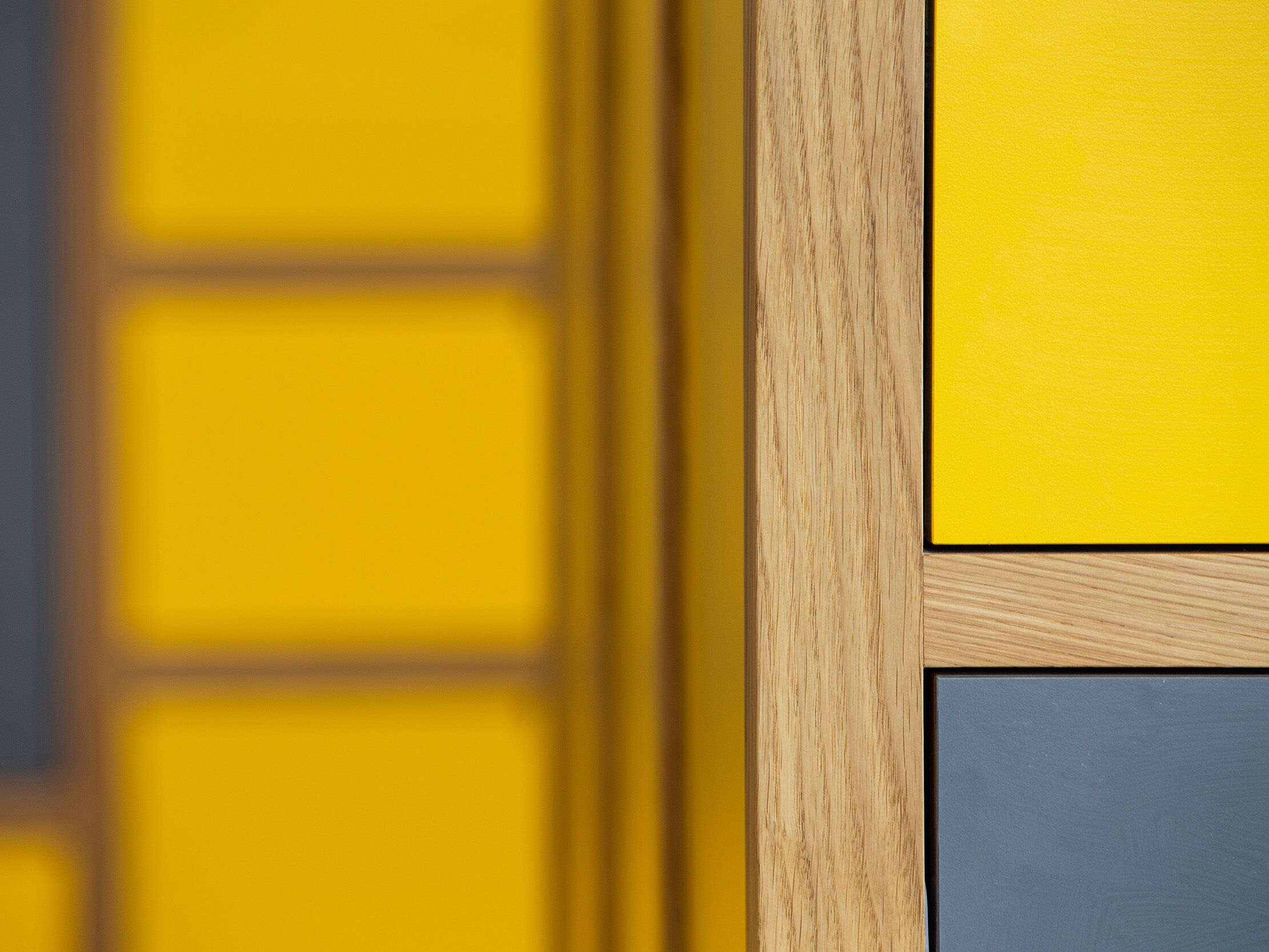 A close-up of a wooden door with a yellow panel and a grey panel.