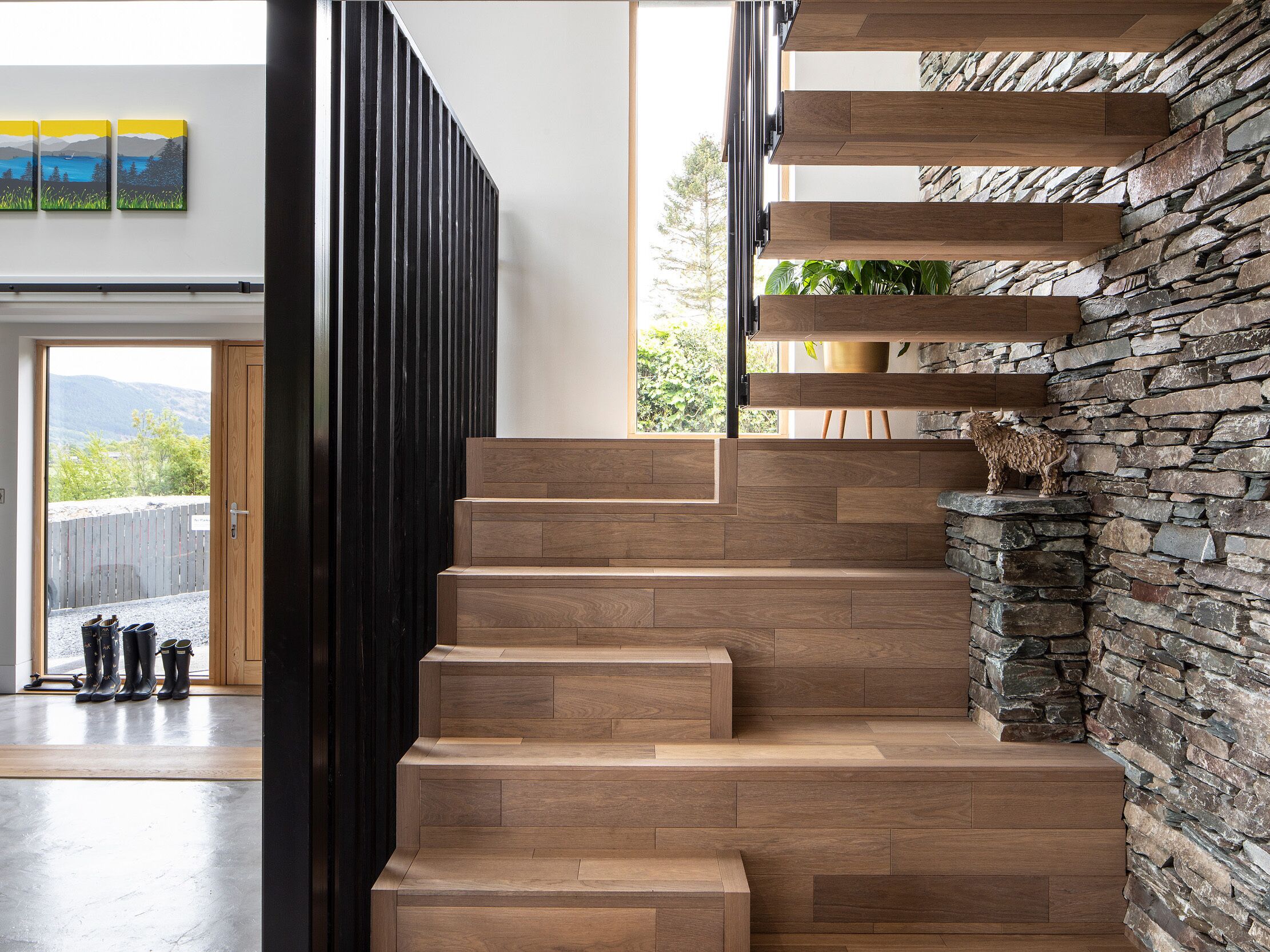 A modern staircase with wooden steps and a stone wall.