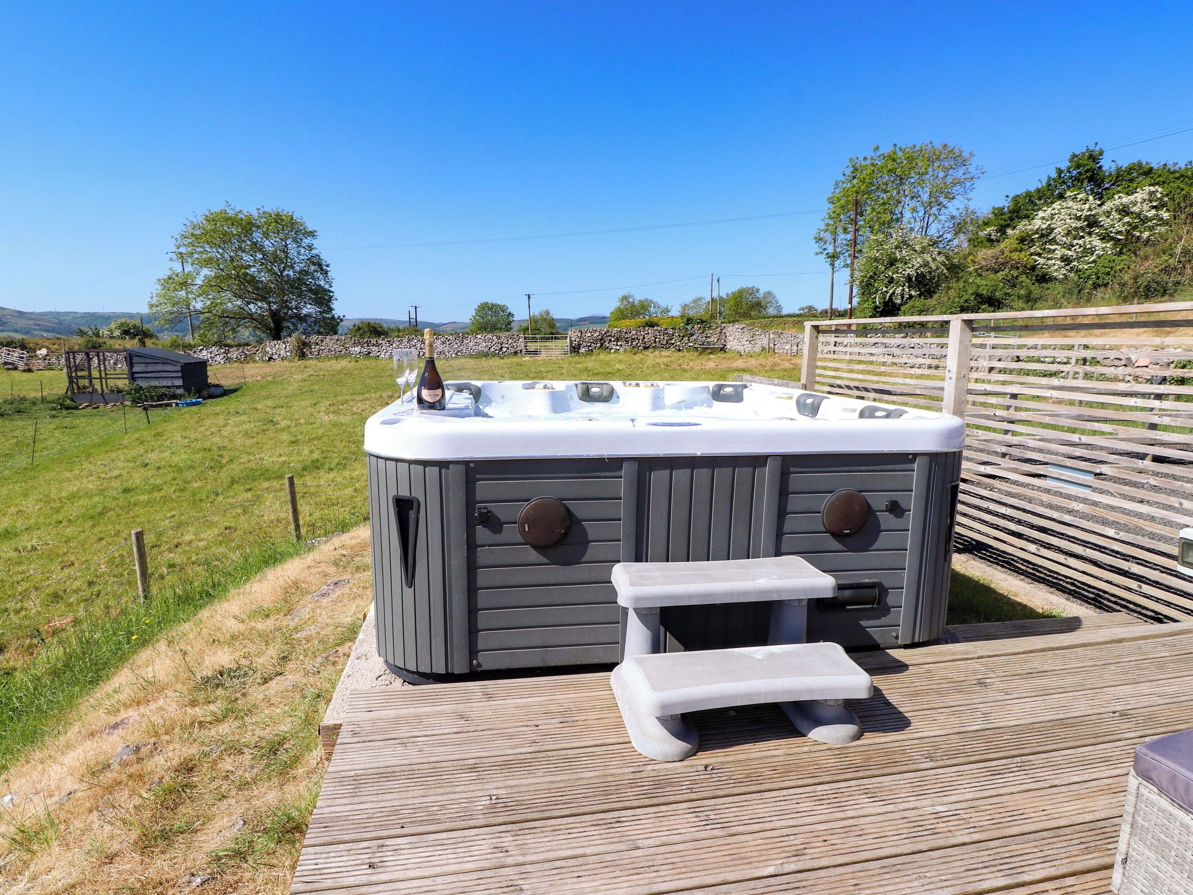 A hot tub with a step stool and a bottle of champagne on a wooden deck.